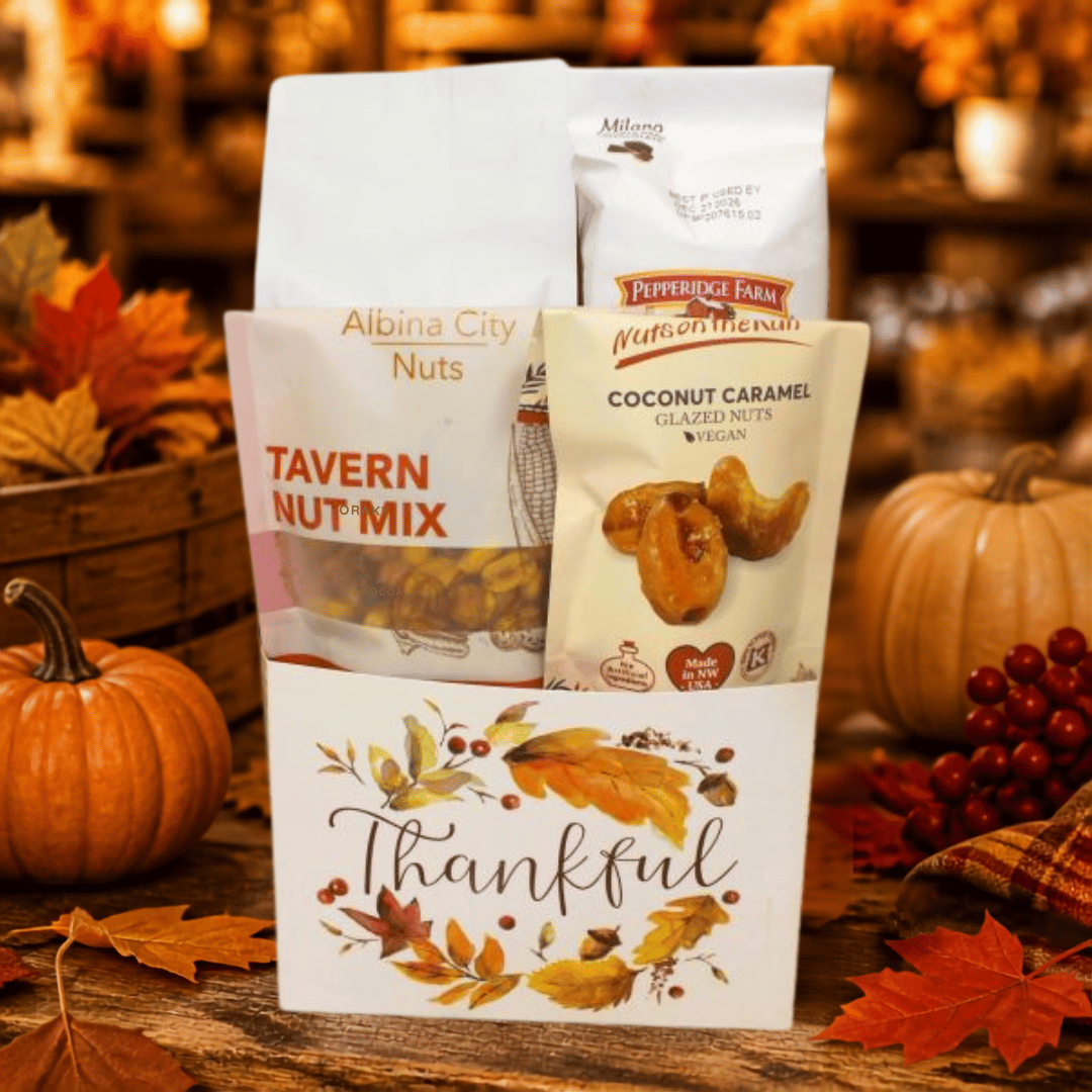 A fall-themed gift basket filled with snack bags, including Albina City Nuts Tavern Nut Mix and Pepperidge Farm Nut & Seed Co. Coconut Caramel, set on a rustic wooden table with pumpkins, autumn leaves, and berries in the background.